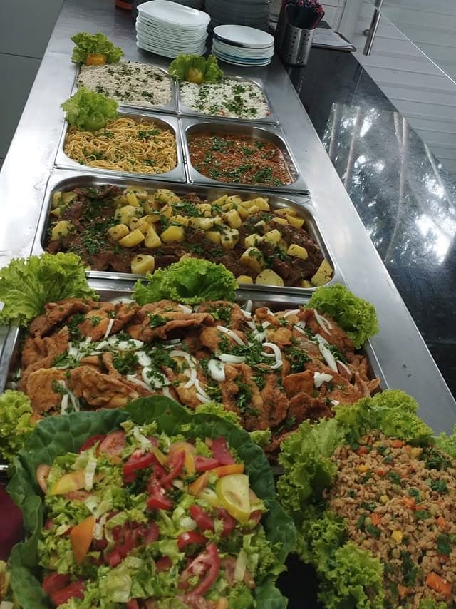 Buffet industrial com variedade de pratos servidos em bandejas inox